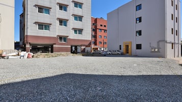 A building with multiple floors, a parking area, and a gravel ground.