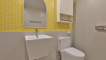 Un baño con lavamanos blanco, inodoro y espejo sobre el lavamanos.