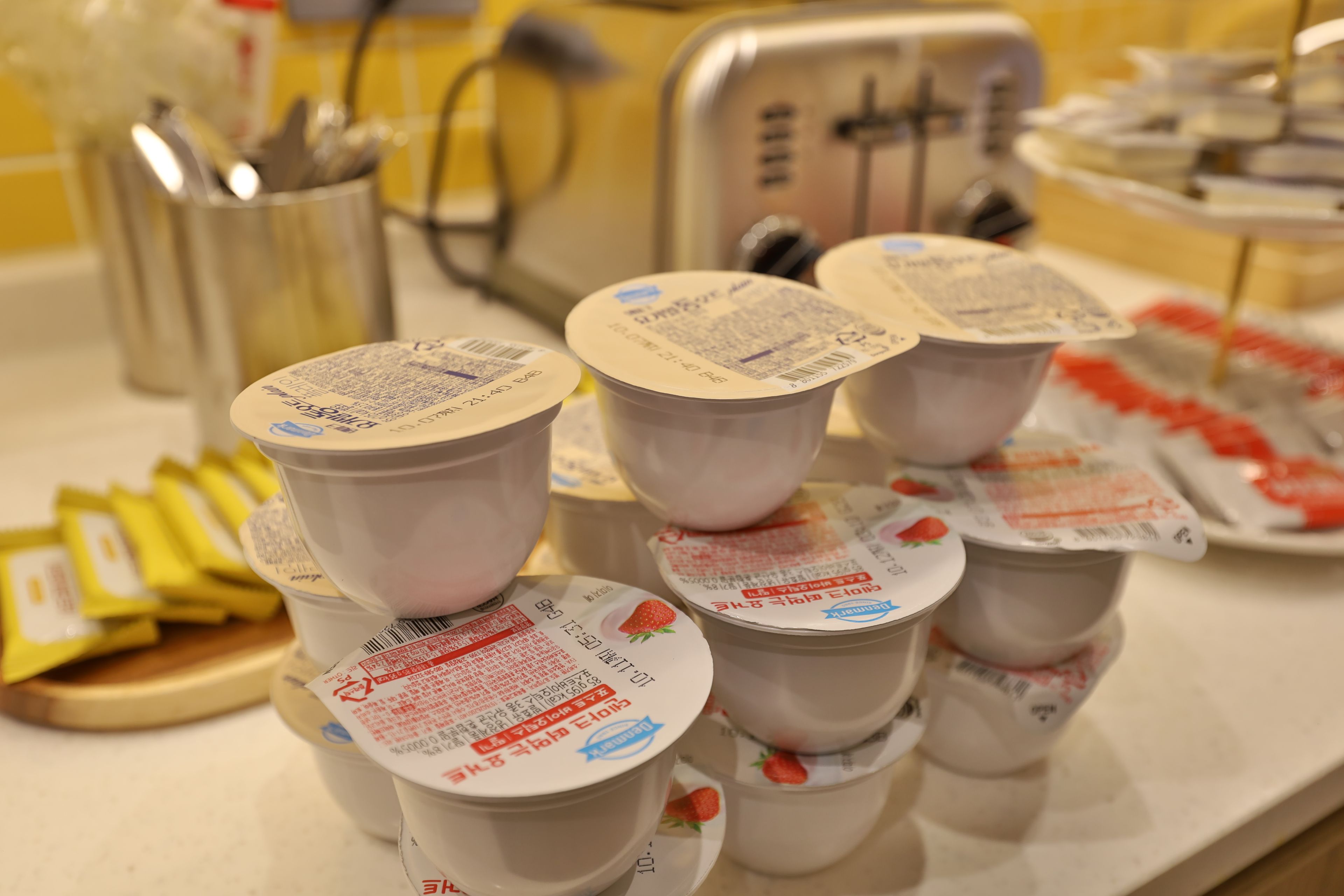 A table with multiple cups of yogurt, some with labels and others without.