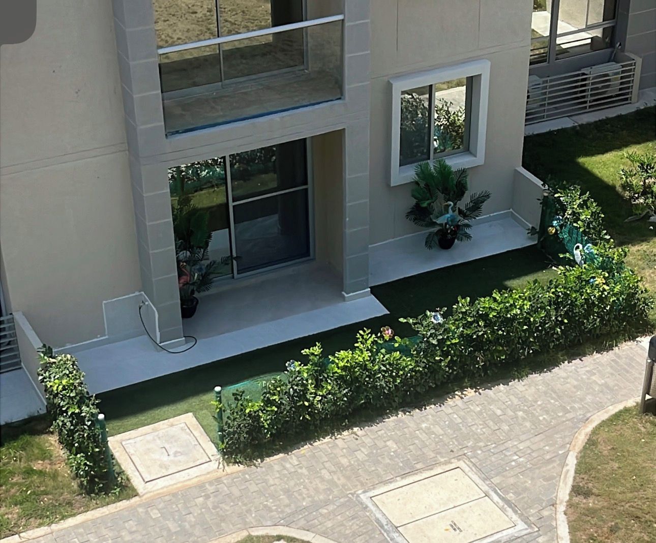Un bâtiment moderne à deux étages, doté d’un balcon, de plantes en pot et d’un chemin pavé.