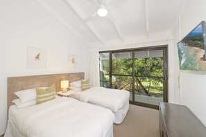 A hotel room with two beds, a nightstand, a lamp, and a large window with a view of a beach and greenery. - Kananda Riverside, Noosa Heads (Noosa Heads)
