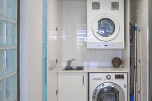 A compact laundry room with a washing machine, a dryer, and a sink. - Kananda Riverside, Noosa Heads (Noosa Heads)