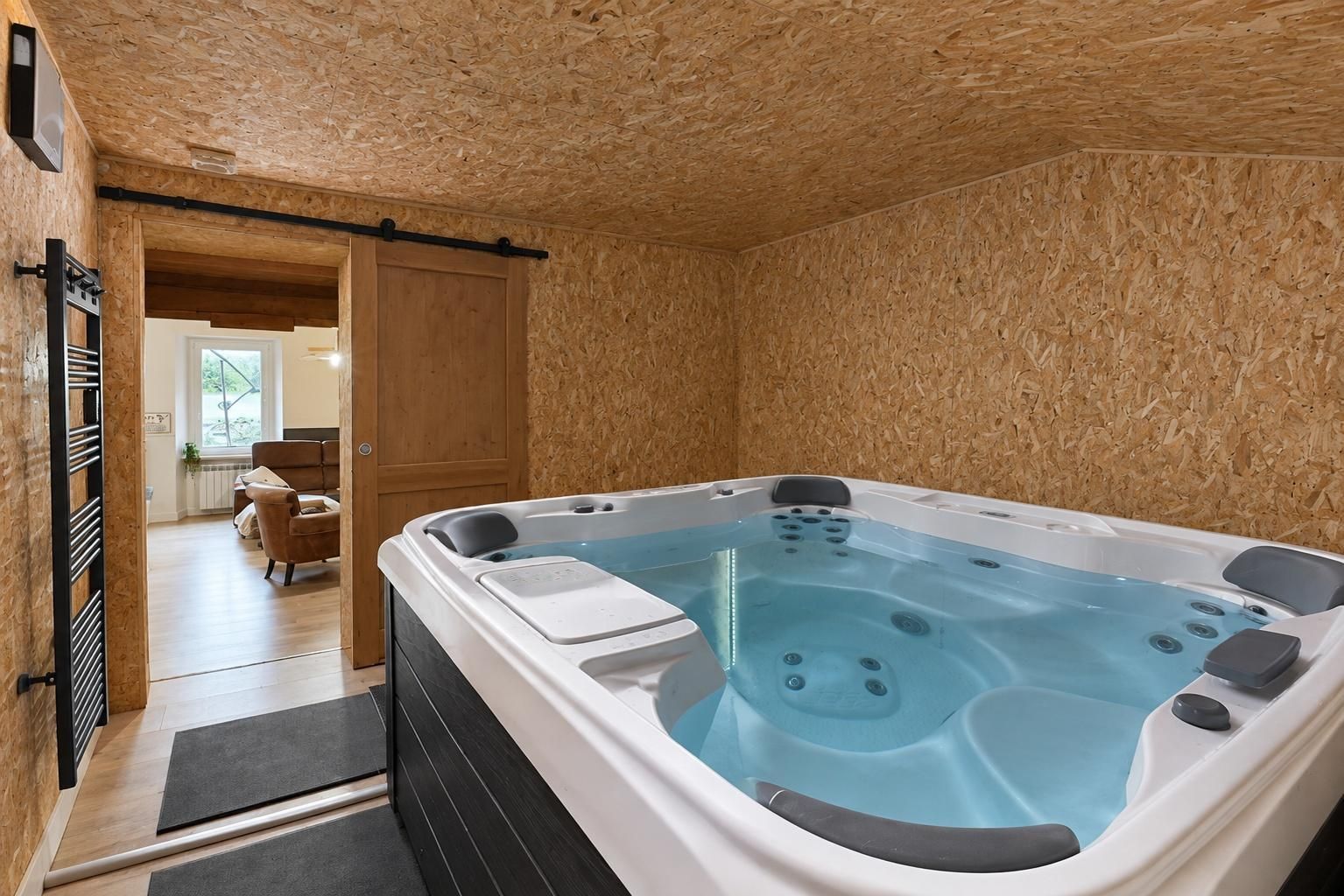 Een bubbelbad in een ruimte met houten wanden en een deur naar een andere kamer.