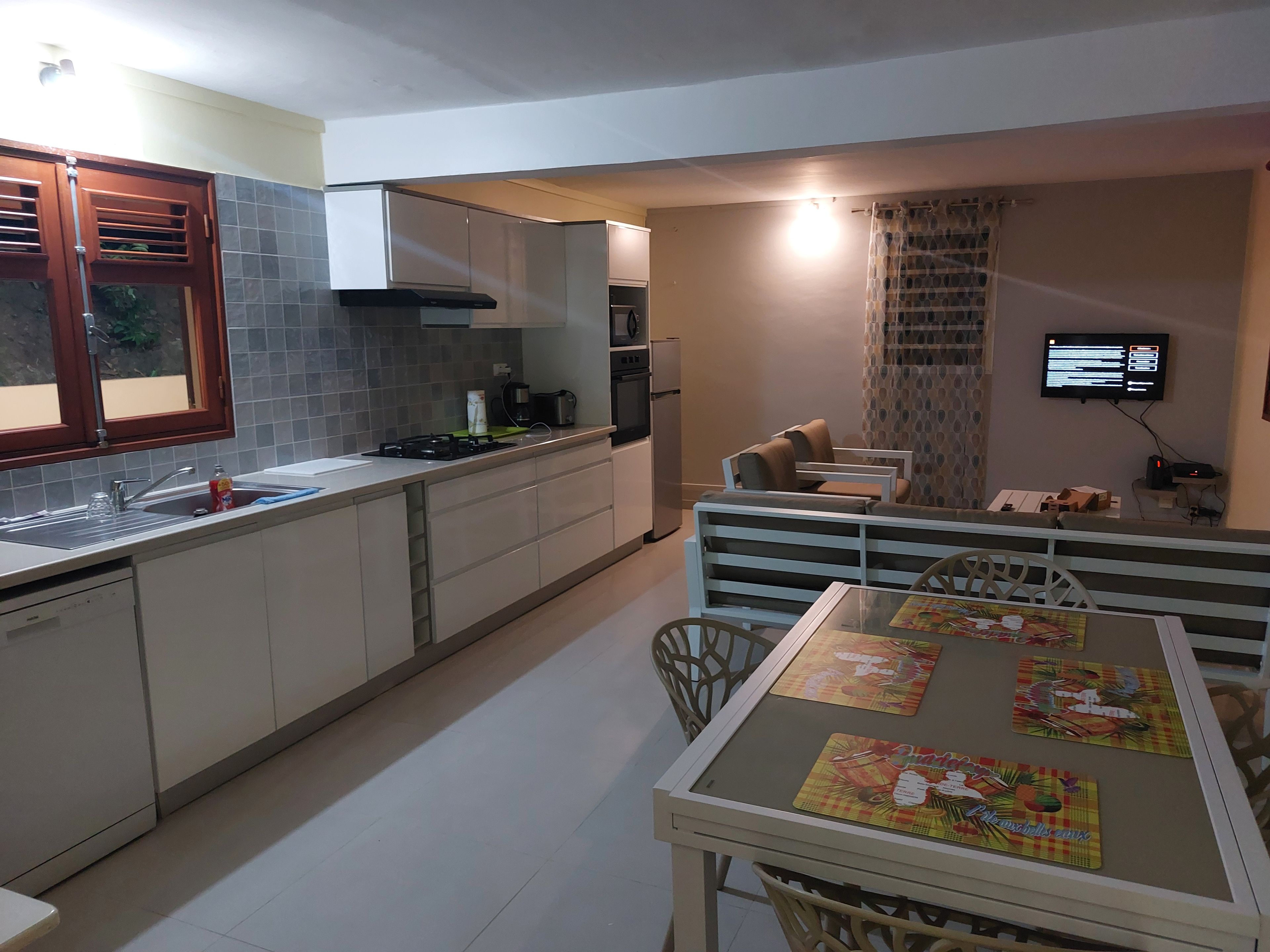 A modern kitchen with a dining area, including a table with placemats and chairs.