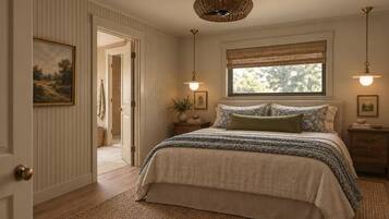 Un dormitorio con cama, ventana con vistas, puerta y lámpara colgante.