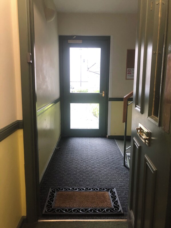 En hall som leder till en dörr med utsikt över omgivningen.