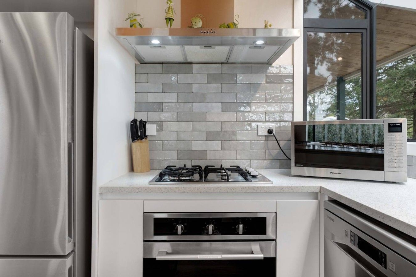 Eine moderne Küche mit einem Edelstahl-Kühlschrank, einem Gasherd, einem Backofen und einer eingebauten Mikrowelle.