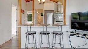 A modern kitchen with a bar area, stainless steel appliances, and a TV. - The Cottage Dairy Flat | Farmhouse Country Escape (Auckland North Shore)