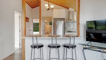 Una cucina moderna con angolo bar, elettrodomestici in acciaio inossidabile e una televisione.