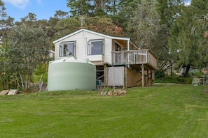 Een herenhuis met een balkon, een grote cilindervormige tank en een keurig onderhouden gazon.