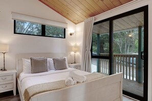 Een slaapkamer met een bed, nachtkastjes, een raam en uitzicht op het groen.