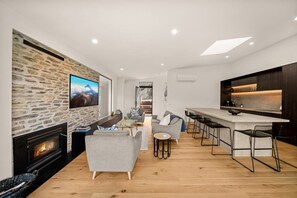 Ein modernes Wohnzimmer mit Steinwand, Kamin, grauen Sofas und einem Fernseher.