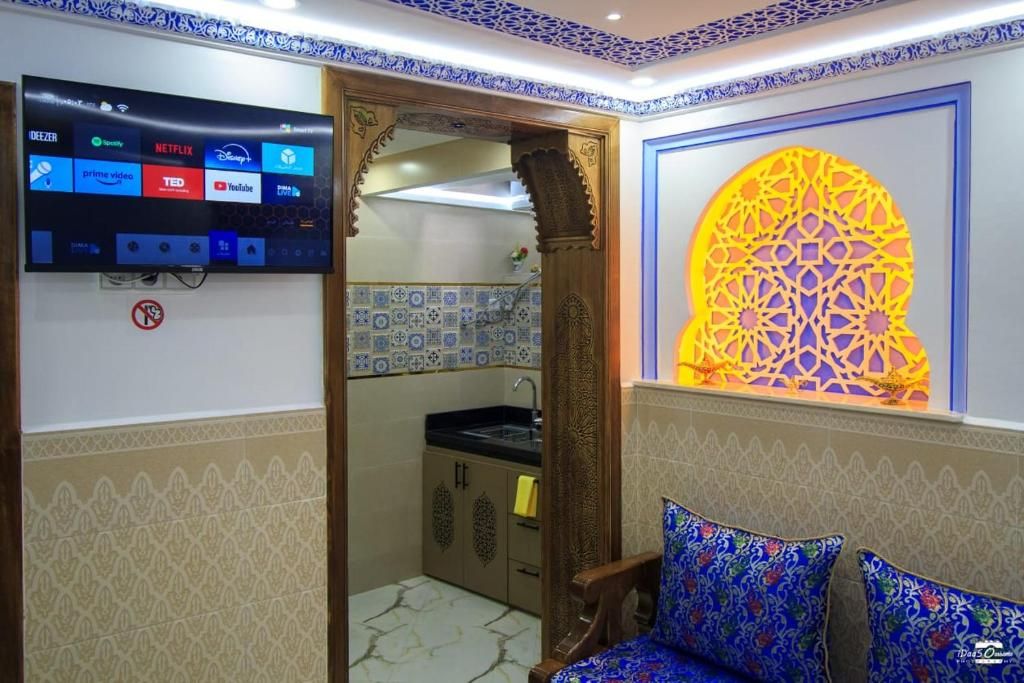 Quarto com televisão exibindo diversos serviços de streaming, um objeto decorativo na parede e um chão estampado.