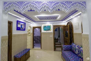 Una habitación con techo estampado, un banco, un sofá y un cuadro en la pared.