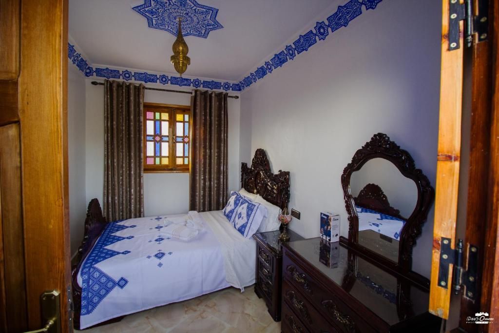 Quarto com cama, cômoda, espelho e janela com cortinas.