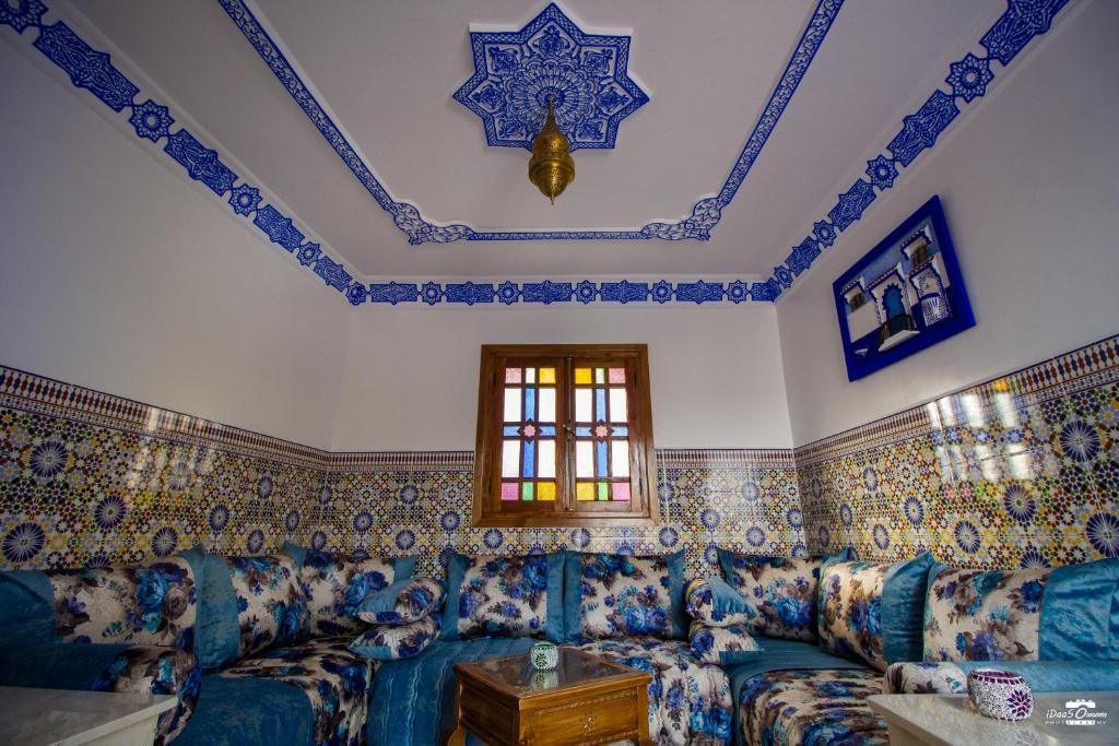 Een kamer met een gestreept sofa, een houten salontafel en een decoratief plafond.