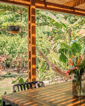Eine hölzerne Pergola mit einem hängenden Blumentopf und einer Hängematte.
