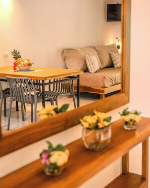 Un comedor con una mesa y sillas de madera, un frutero y un sofá con cojines.