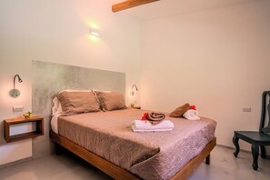 Ein Schlafzimmer mit einem großen Bett, zwei Nachttischen, einem Sessel und Wandleuchten.
