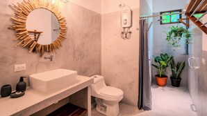 A bathroom with a modern design, including a white sink, toilet, and a mirror with a unique wooden frame. There are potted plants and a shower area visible. - Lapas · Jungle House for 4 + Pool +AC · Walk to Beach · Cabuya (Cabuya)