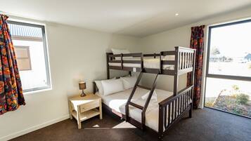 A bunk bed room with a window, a bedside table, and a view of the outside.