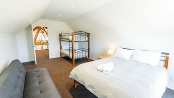 A bedroom with a bunk bed, a single bed, a sofa, and a nightstand with a lamp.
