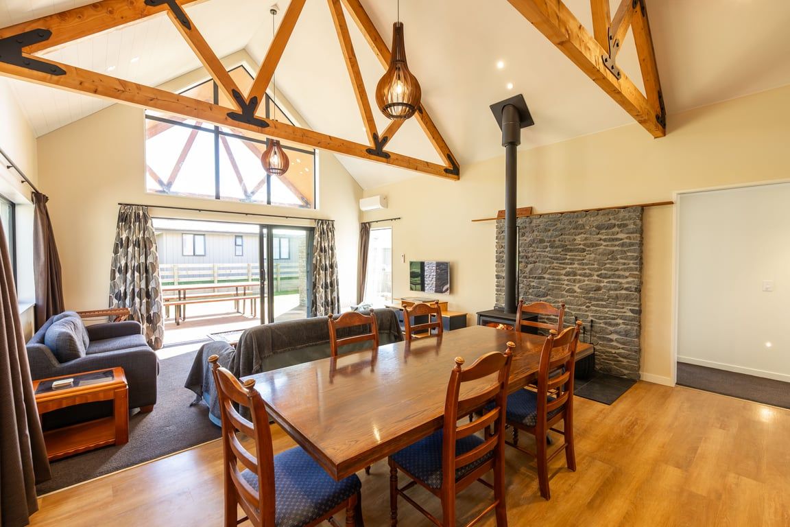 A spacious living area with a wooden dining table, comfortable seating, and a stone fireplace.