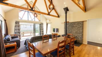 A spacious living area with a wooden dining table, comfortable seating, and a stone fireplace.