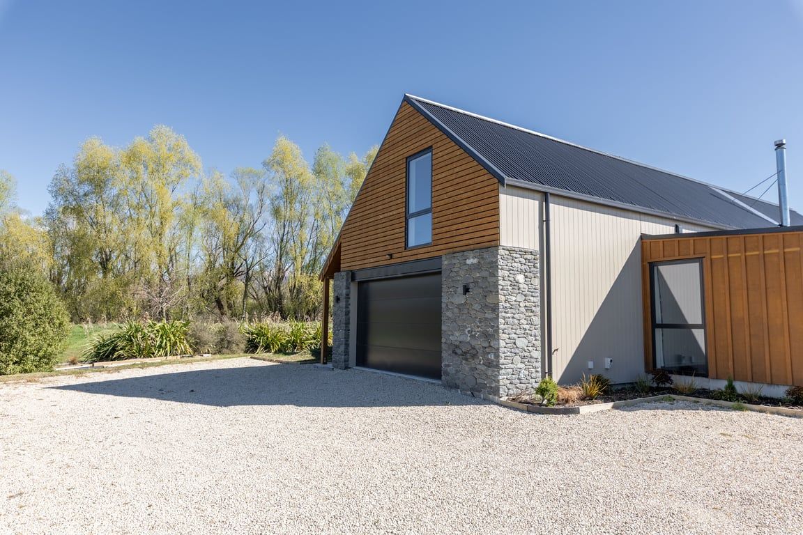 A modern house with a garage, stone facade, and a sloped roof.