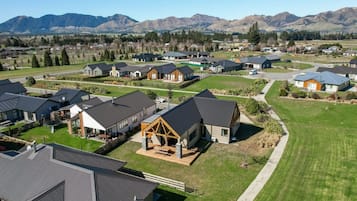 A residential area with houses featuring modern architecture, surrounded by a well-maintained lawn and a mountain backdrop.