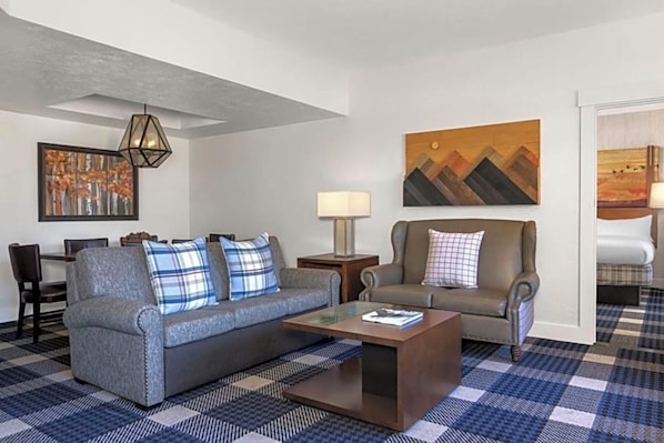 A living room with a sofa, a coffee table, a lamp, and a painting on the wall.