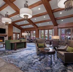 A spacious lobby with a stone fireplace, wooden beams, and a large seating area with a fireplace.