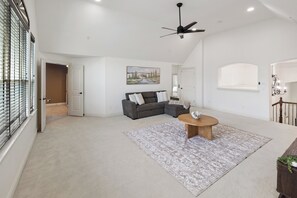 A spacious living room with a grey sectional sofa, a round coffee table, and a patterned rug. - 5BR Frisco Retreat Near Universal Kids Resort/PGA (Frisco)