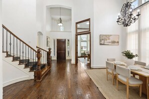 A spacious interior with a wooden staircase, a dining area, and a chandelier. - 5BR Frisco Retreat Near Universal Kids Resort/PGA (Frisco)