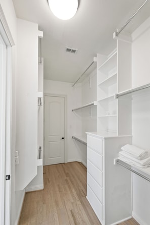 A walk-in closet with open shelving, a door, and a light fixture. - 5BR Frisco Retreat Near Universal Kids Resort/PGA (Frisco)