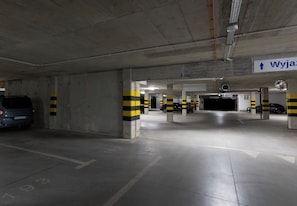 Eine Tiefgarage mit Betonstützen, markierten Stellplätzen und Hinweisschildern.