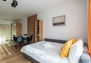 Una habitació d'hotel moderna amb un llit, zona de menjador i vista al mar.