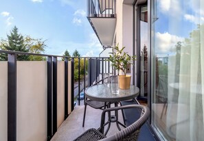 Ein Balkon mit Glastisch, Stühlen und einem Blumentopf.