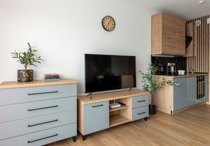 Ein modernes Wohnzimmer mit Flachbildfernseher, einer Wanduhr und einer Küchenzeile mit Holzausbau.