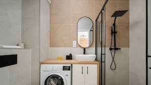 Un baño moderno con lavadora, lavamanos y ducha.
