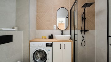 Un baño moderno con lavadora, lavamanos y ducha.
