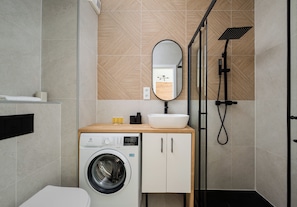Un baño moderno con lavadora, lavamanos y ducha.