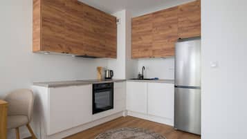 A modern kitchen with wooden cabinets, a stainless steel refrigerator, and a built-in oven.