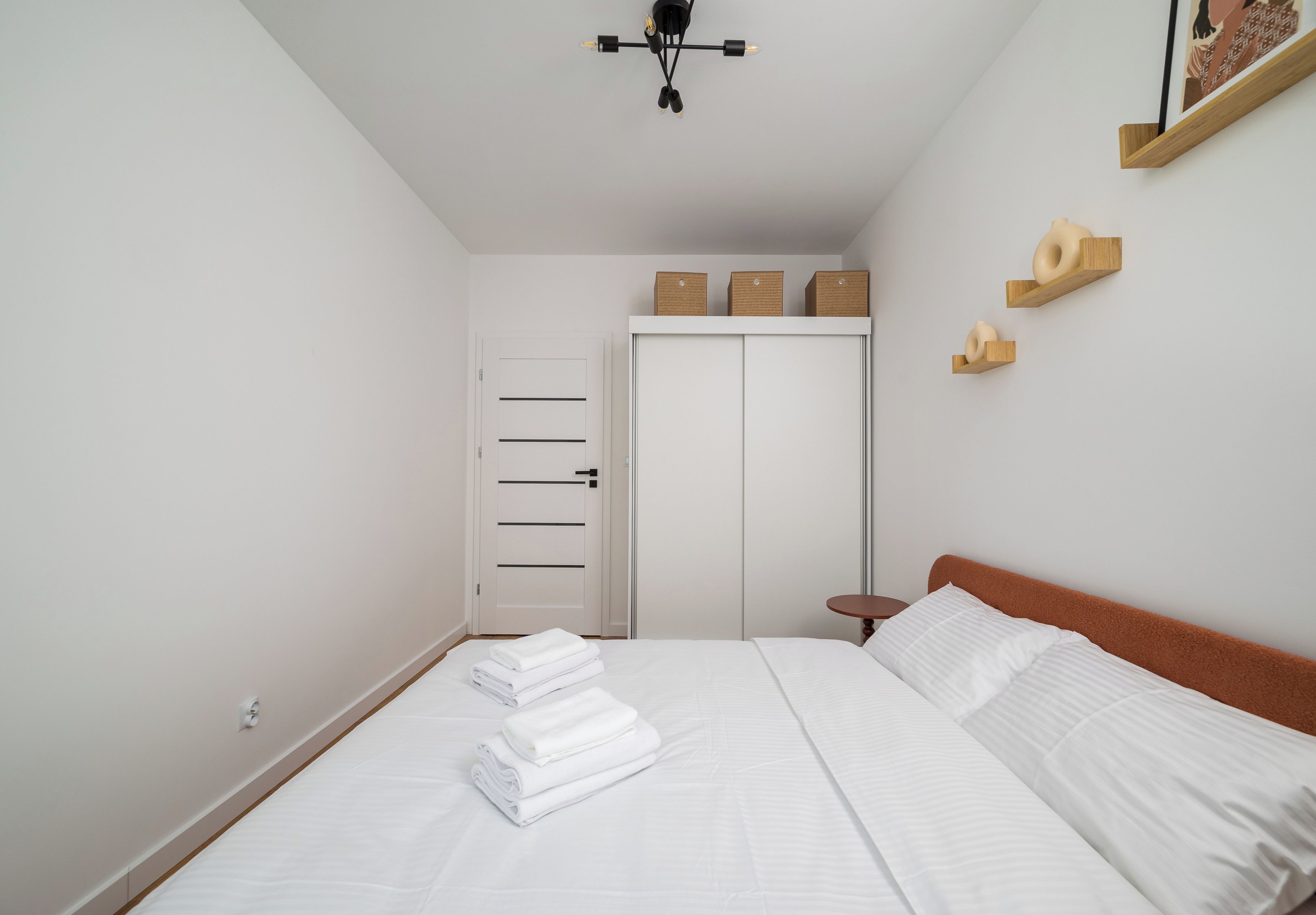 Un dormitorio con cama, armario, mesita de noche y lámpara colgante.