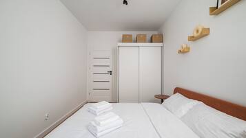 Un dormitorio con cama, armario, mesita de noche y lámpara colgante.