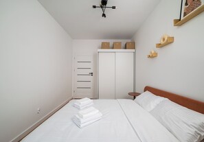 Quarto com cama, guarda-roupa, mesa de cabeceira e luminária pendente.