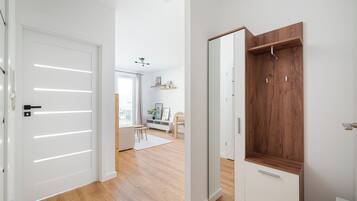 Un interior moderno con suelo de madera, paredes blancas y un armario de madera con barra para colgar.