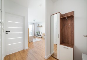 Interior moderno com piso de madeira, paredes brancas e um guarda-roupa de madeira com cabideiro.
