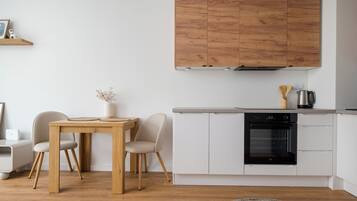 Una cocina moderna con armarios blancos, una mesa de comedor de madera y sillas.