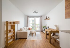 Uma sala de estar moderna com sofá, mesa de jantar com cadeiras, estante de madeira e luminária no teto.